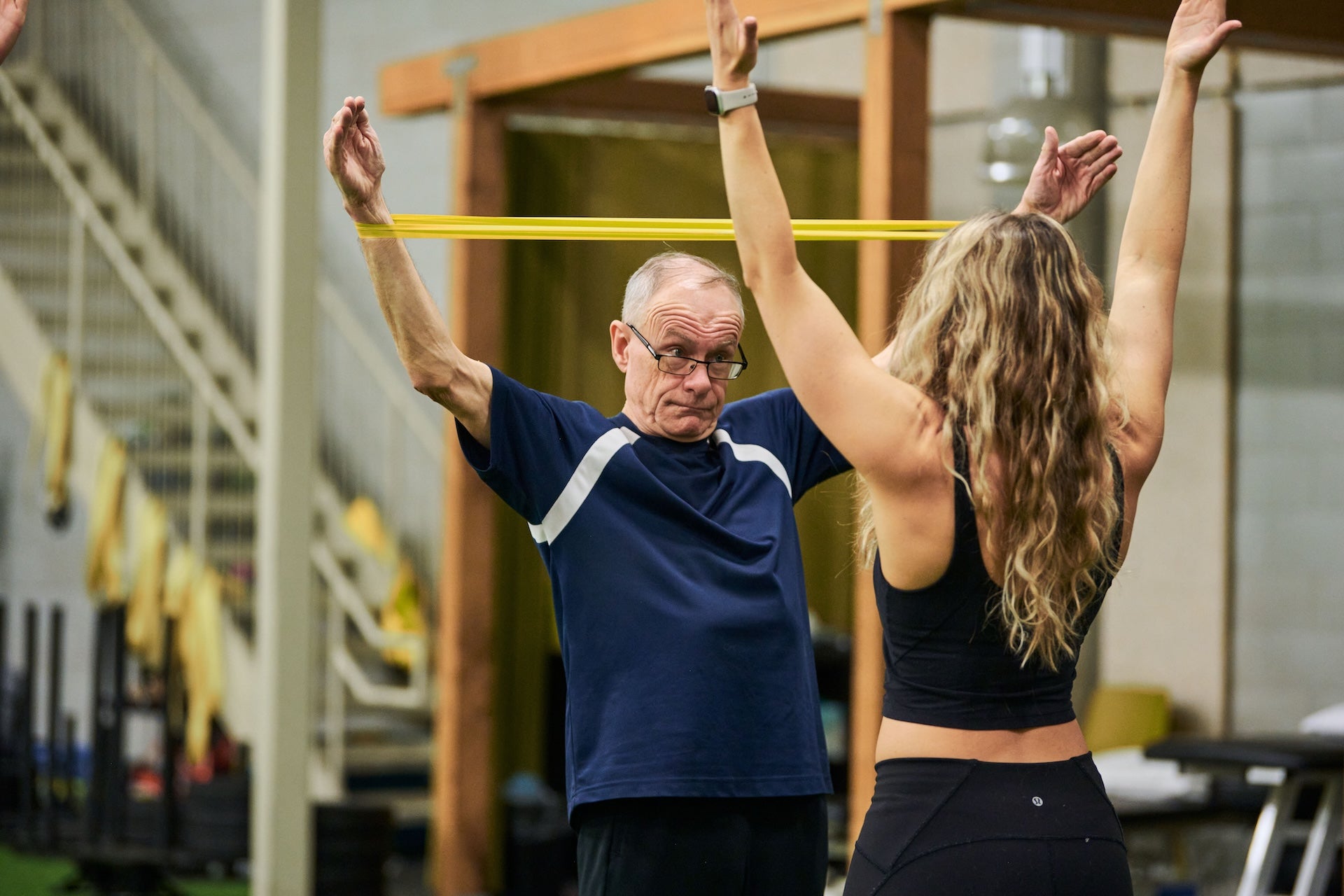 Group fitness coach Emma Bissonette demonstrates a shoulder warmup exercise to a group fitness member during a group fitness class at Group fitness members at Human 2.0 Ottawa Physiotherapy, Massage, & Gym South Keys Location