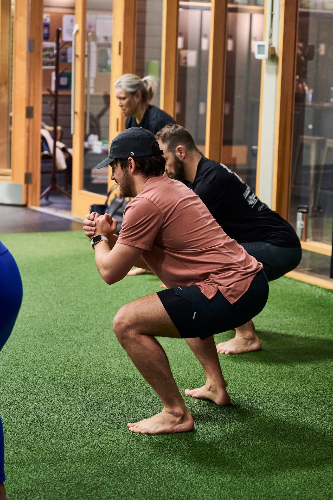 Group fitness members performing bodyweight squat exercise during a group fitness class at a Human 2.0 Ottawa Physiotherapy, Massage, & Gym South Keys Location